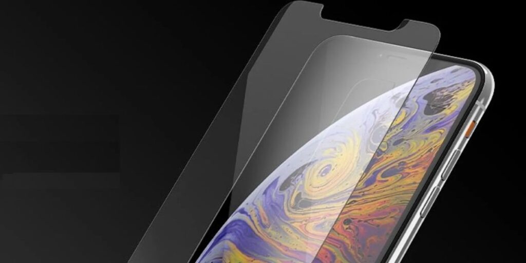 A clear glass screen protector is being carefully placed onto a smartphone screen.
