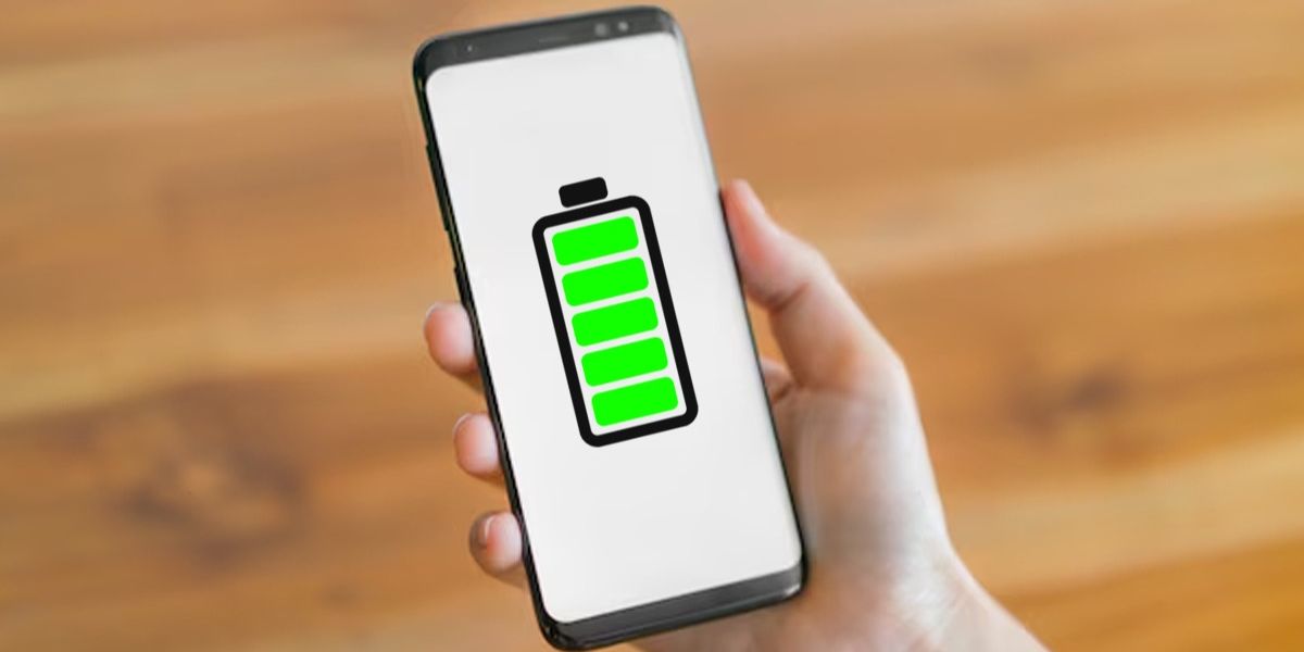 Hand holding a smartphone displaying a full green battery icon on the screen