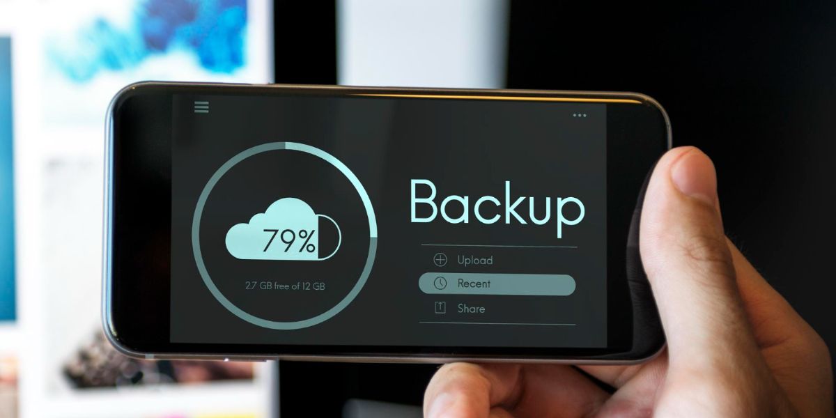 Hand holding a smartphone that displays a "Backup" screen with a cloud icon and 79% progress